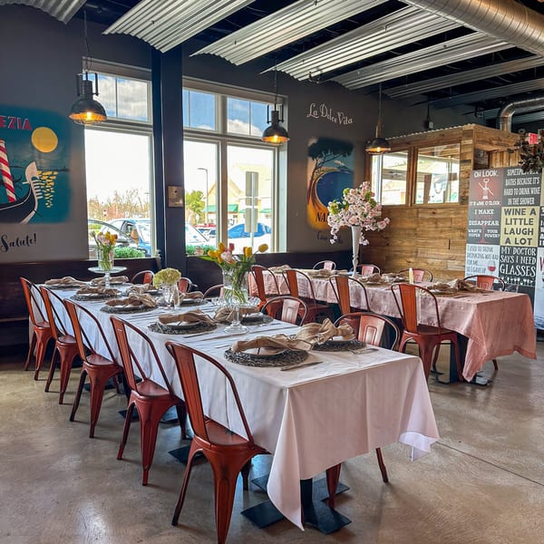 Bacco Centro's dining room with set tables, orange chairs, and Italian-themed wall art.