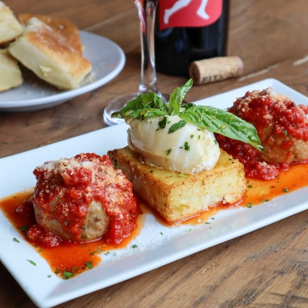 Bacco Centro's meatballs with tomato sauce, polenta, fresh mozzarella, and basil, with wine and bread.